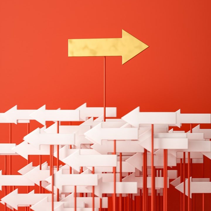 Weiße Pfeile auf rotem Hintergrund nach links zeigend, mit einem hervorgehobenen gelben Pfeil nach rechts.