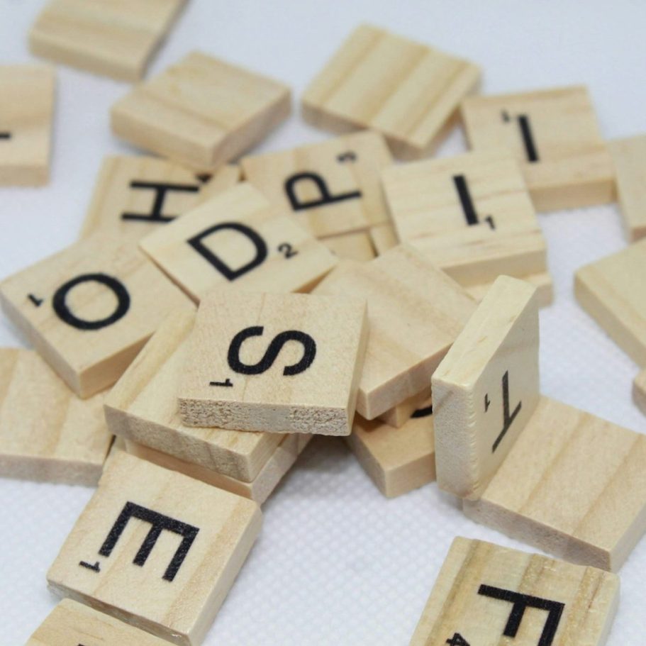 Buchstaben-Chaos Holzbuchstaben mit schwarzer Schrift, zufällig auf einer weißen Oberfläche verteilt.