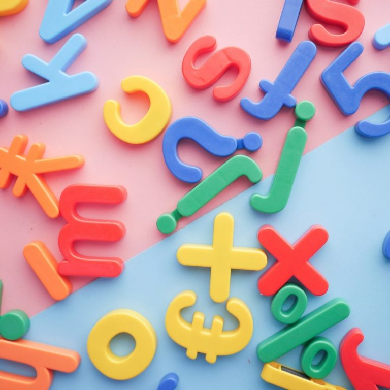 Bunte Buchstaben und Zahlen Bunte Buchstaben und Zahlen aus Kunststoff auf einem zweifarbigen Hintergrund.