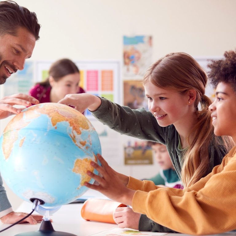 Eine Gruppe von Kindern und einem Lehrer erkundet einen Globus.