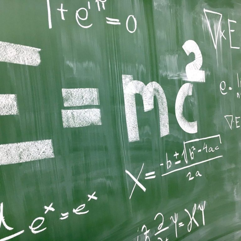 Mathematik und Formeln Formeln auf einer Tafel, einschließlich Einsteins Gleichung E=mc² und weitere mathematische Ausdrücke.